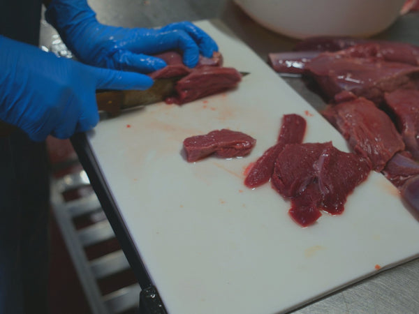 京都・舞鶴の加工場で、鹿肉を包丁で一枚ずつ薄く切る手元